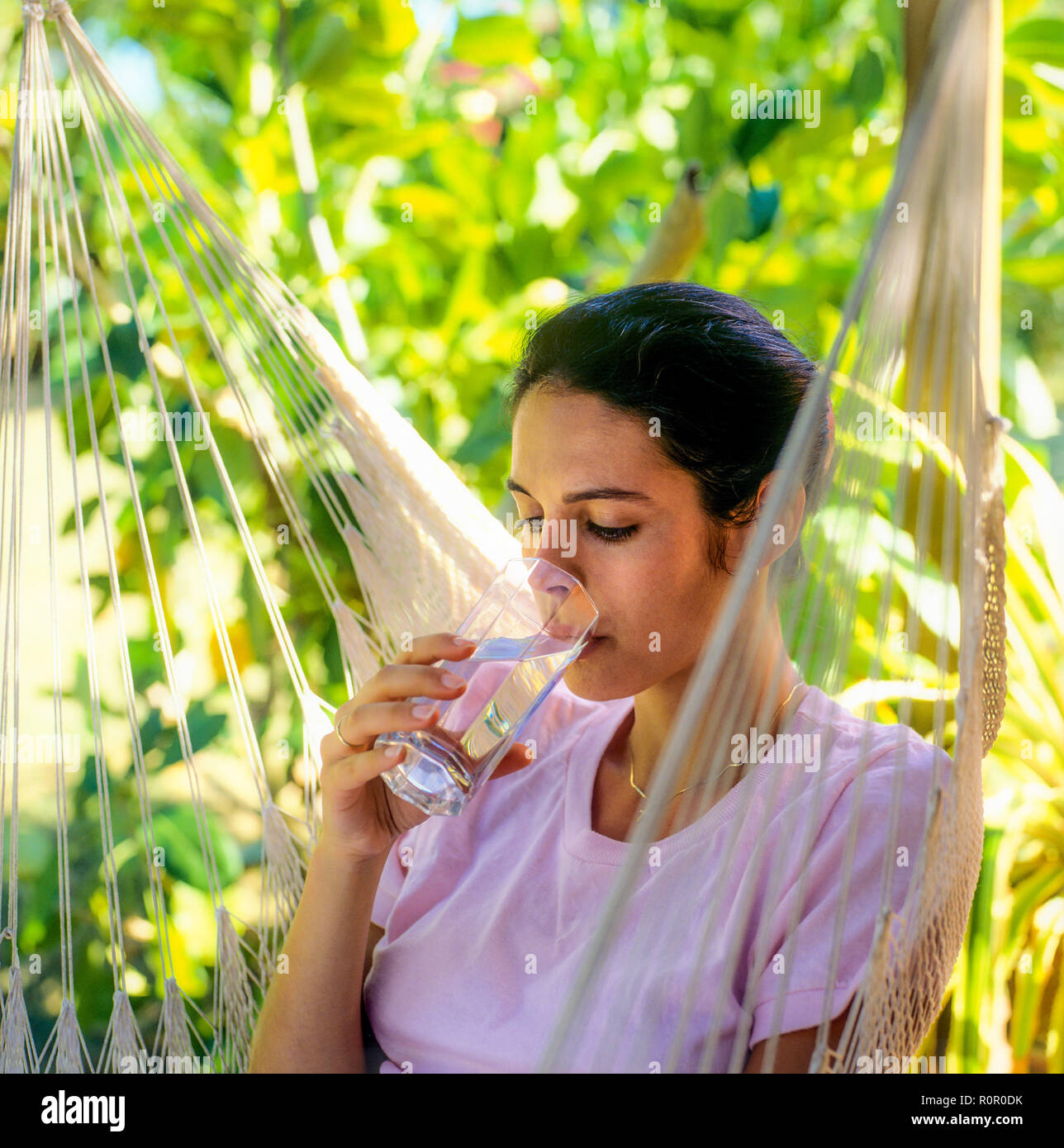 Junge Frau, die ein Glas Wasser trinkt, tropischen Garten, Guadeloupe, Französisch-Westindien Stockfoto