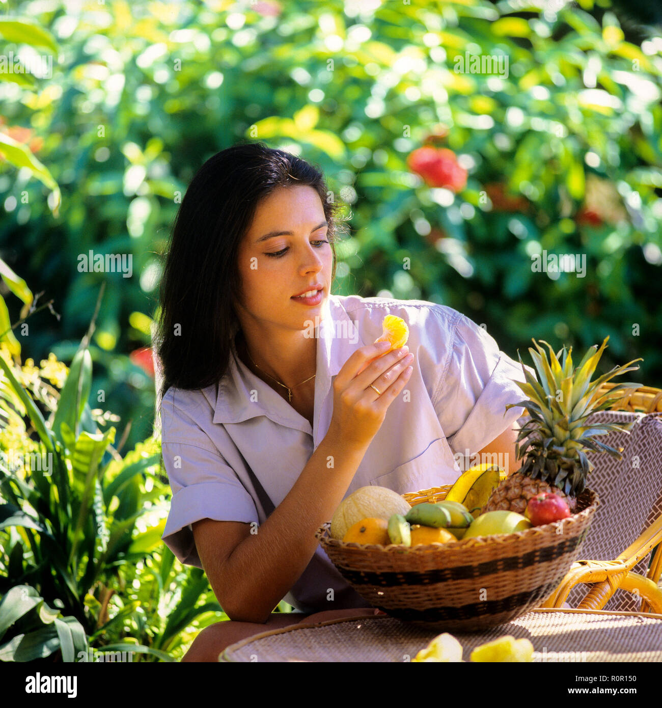 Junge Frau, die exotische Früchte im tropischen Garten, Guadeloupe, Französisch-Westindien isst, eine fittige Frau, die Früchte isst Stockfoto