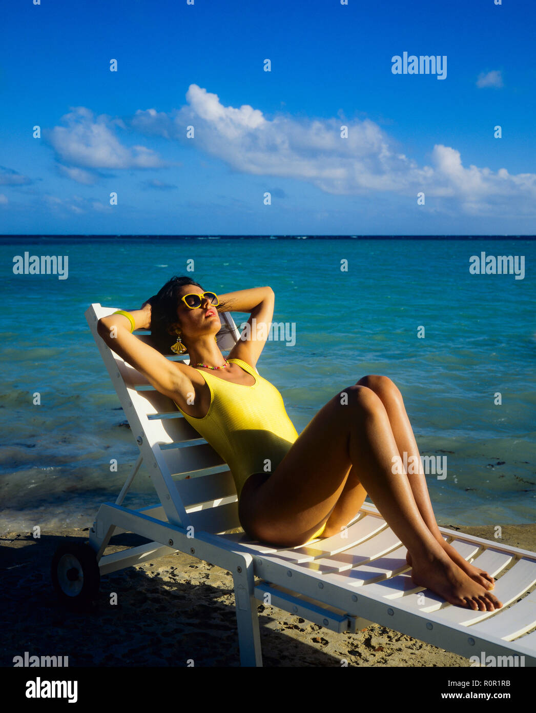 Junge Frau mit gelben Badeanzug Sonnenbaden und Relaxen im Liegestuhl, tropischen Strand, Karibik, Guadeloupe, Französisch Westindien, Stockfoto