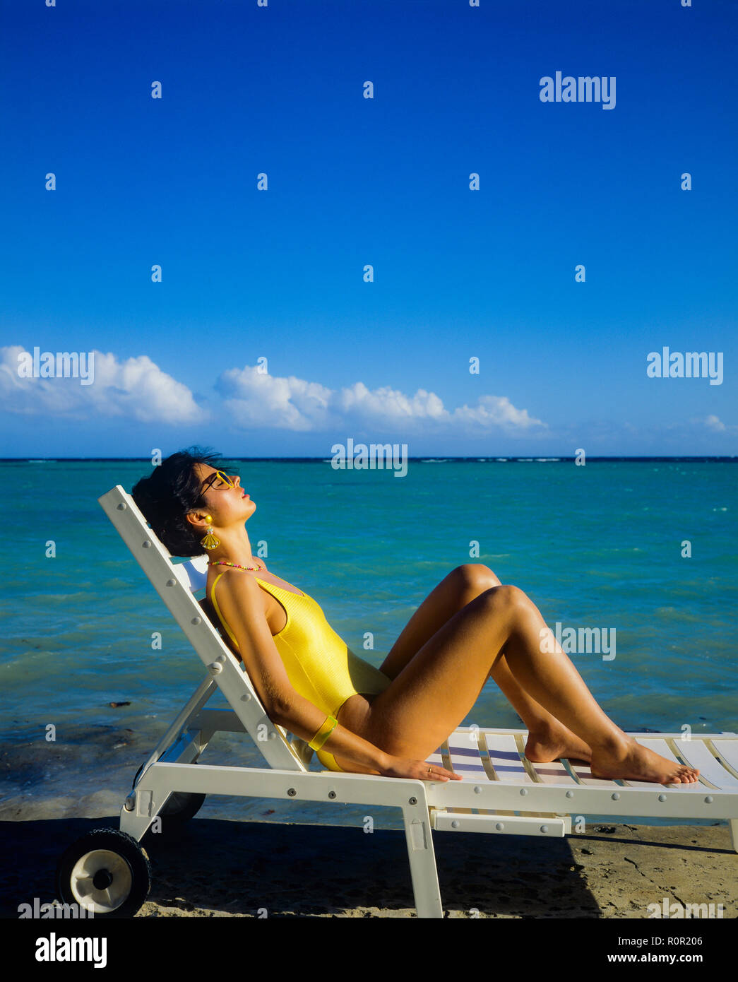 Junge Frau mit gelben Badeanzug Sonnenbaden und Relaxen im Liegestuhl, tropischen Strand, Karibik, Guadeloupe, Französisch Westindien, Stockfoto