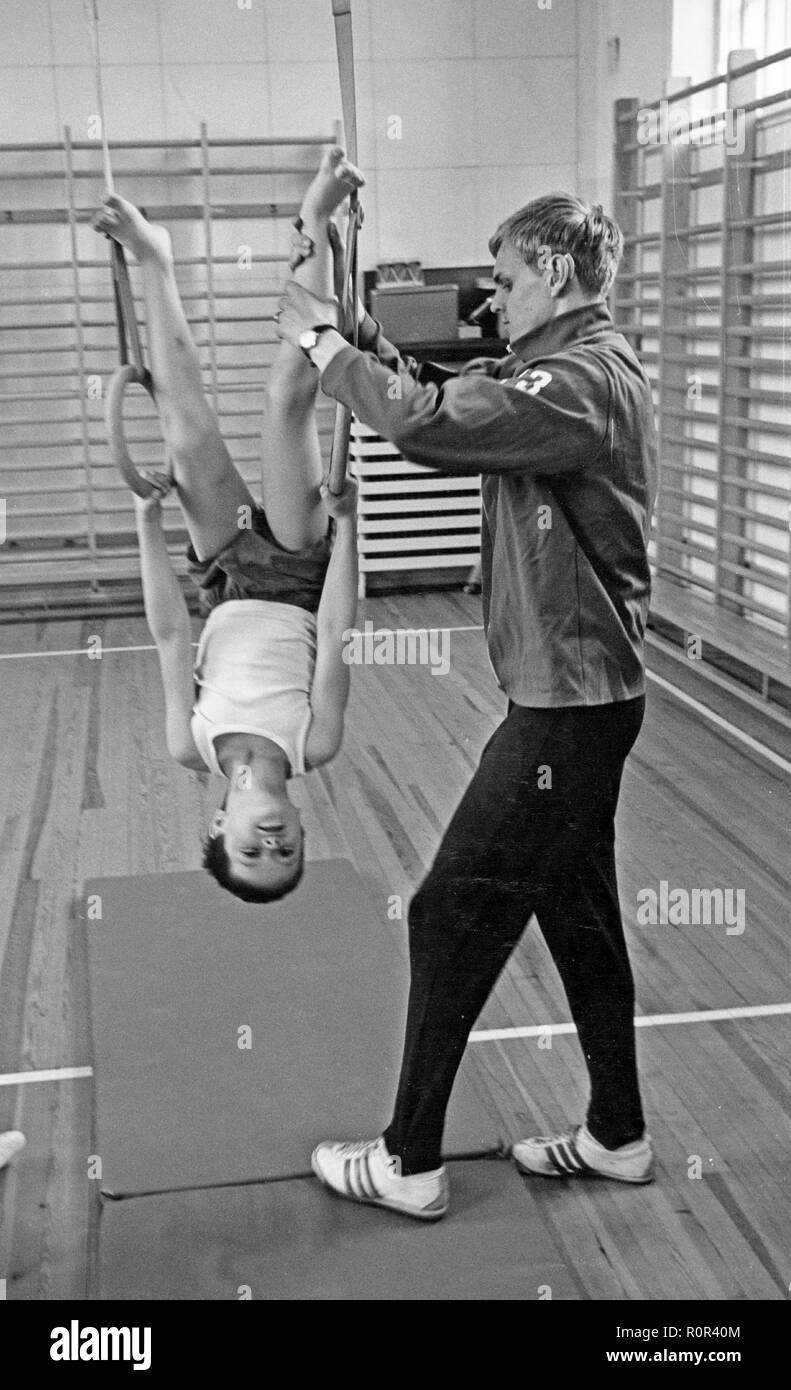 Schule Gymnastik in den 1970er Jahren. Ein Lehrer hilft einem Jungen balancing während Gymnastik Klasse. Schweden 1970 s Stockfoto