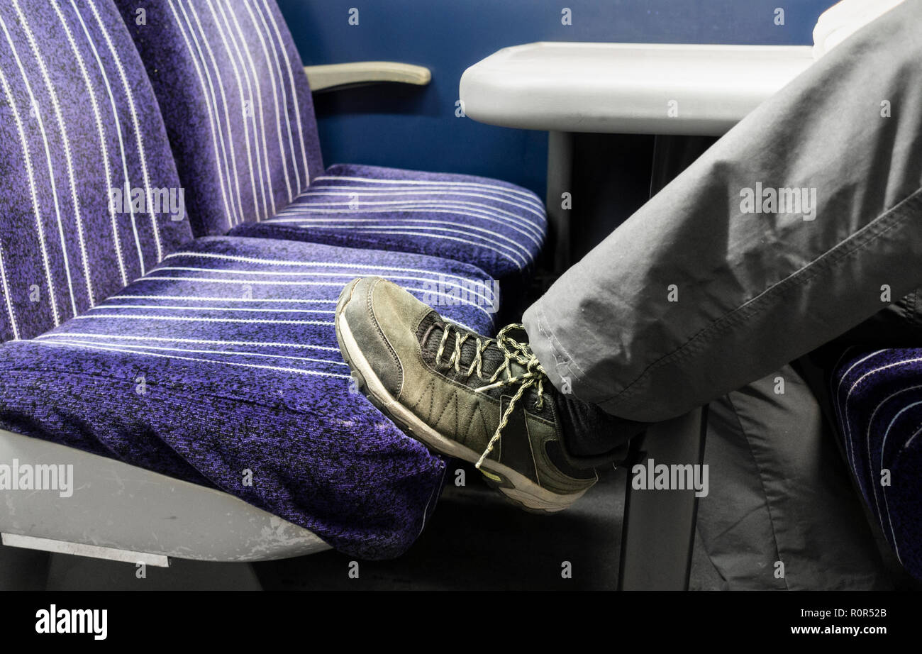 Zug Passagier mit Fuß auf dem Sitz. Großbritannien Stockfoto