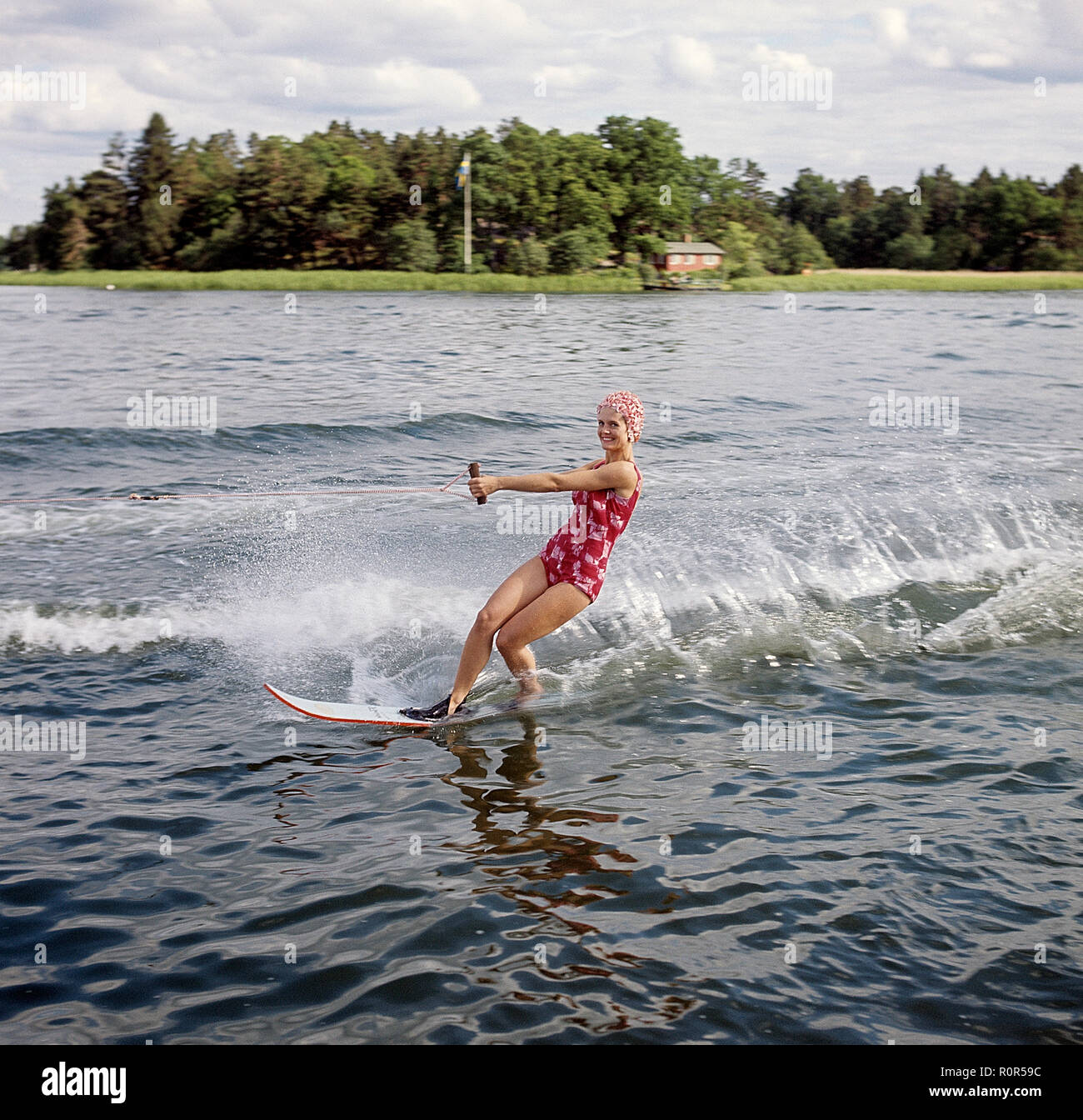 Wasserski in den 1960er Jahren. Eine junge Frau in einem gemusterten Badeanzug übergibt die Fotografen auf ihre Wasserski. Sie hat eine typische Badekappe auf. Schweden 1946 Foto Kristoffersson ref CV 12-7 Stockfoto