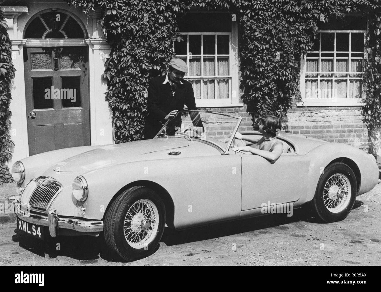 MG in den 1950er Jahren. Britische Automobilhersteller MG startet das neue Modell Sport MGA. Das Auto hat eine vier-cylindre Motor. Ein junges Paar Posen mit dem Auto in einer typischen Umgebung. Stockfoto