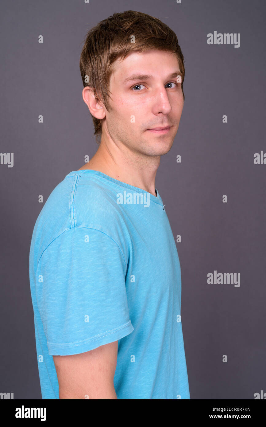 Porträt der jungen gutaussehenden Mann gegen grauer Hintergrund Stockfoto