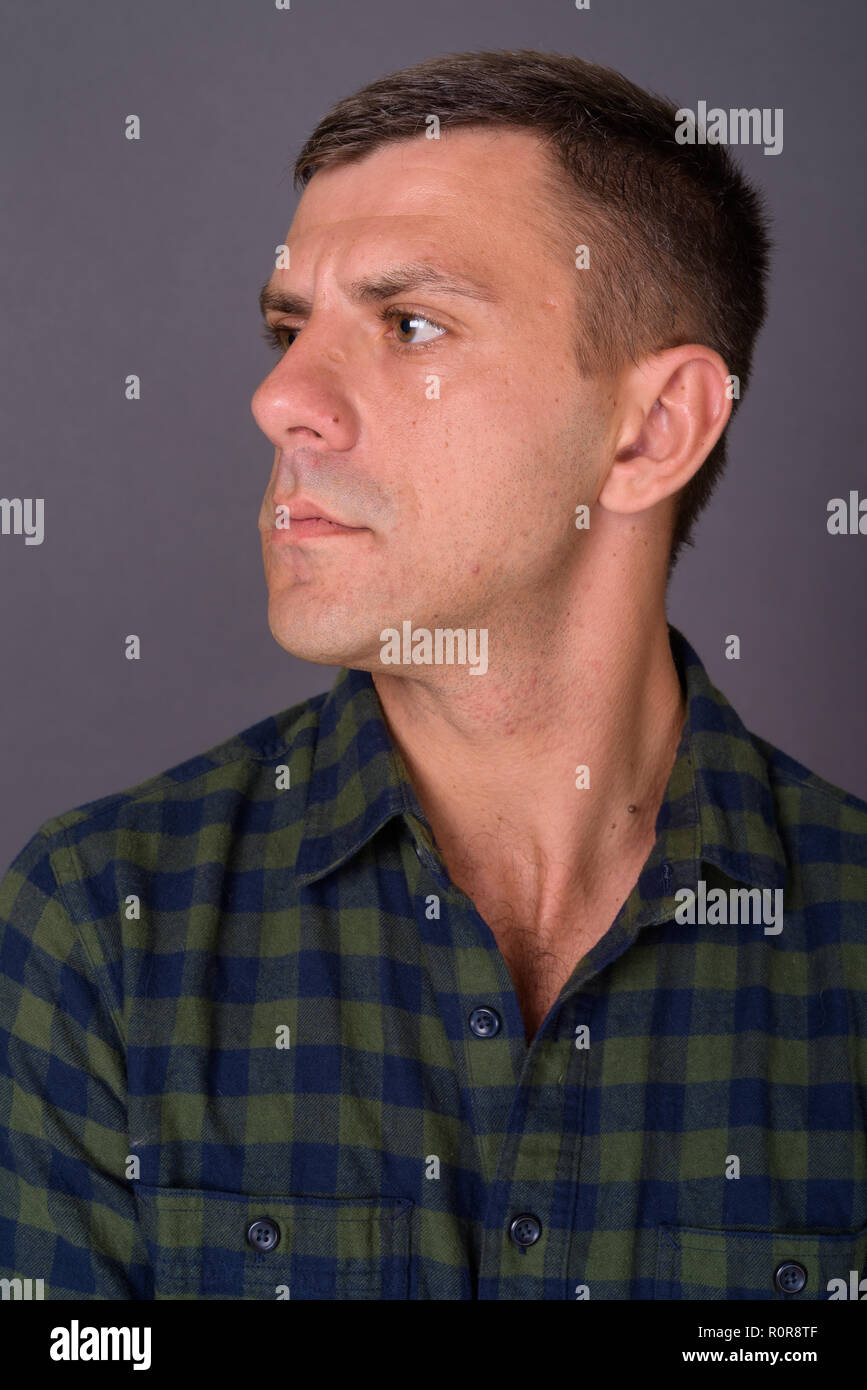 Stattlicher Mann mit kurzen Haaren gegen grauer Hintergrund Stockfoto