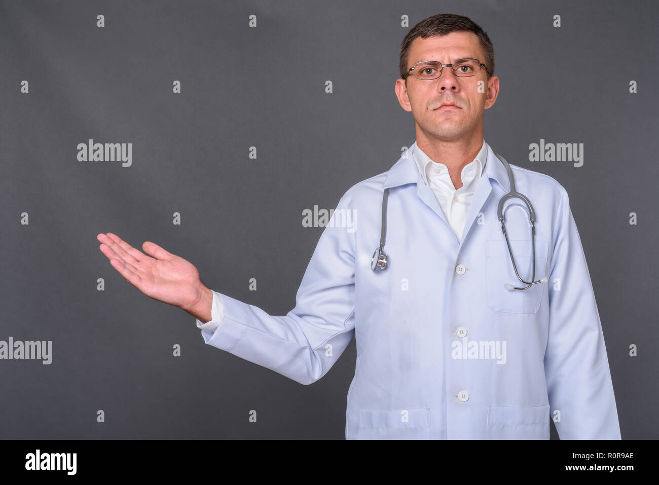 Schöner mann Arzt mit kurzen Haaren gegen grauer Hintergrund Stockfoto