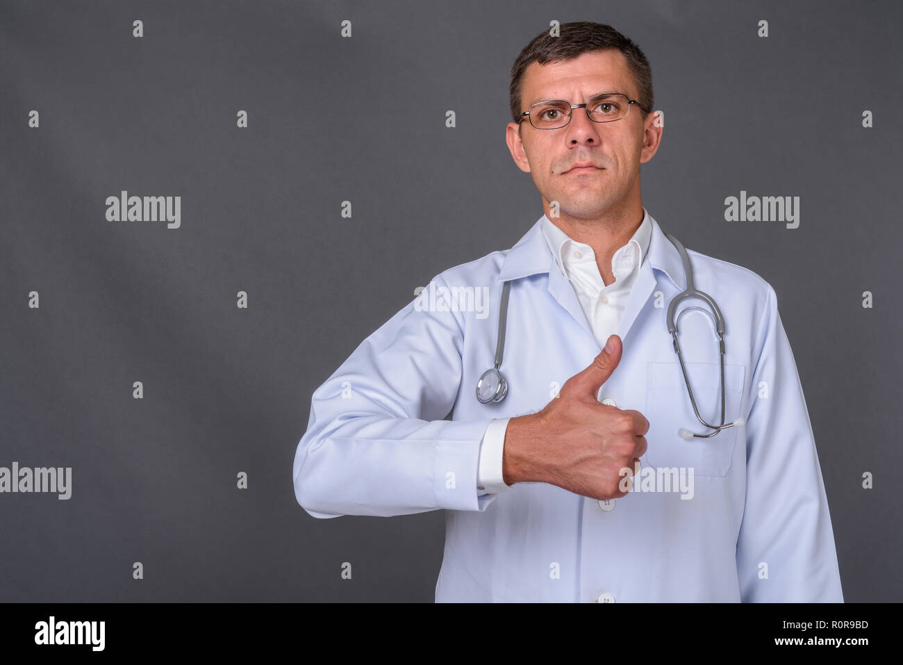 Schöner mann Arzt mit kurzen Haaren gegen grauer Hintergrund Stockfoto