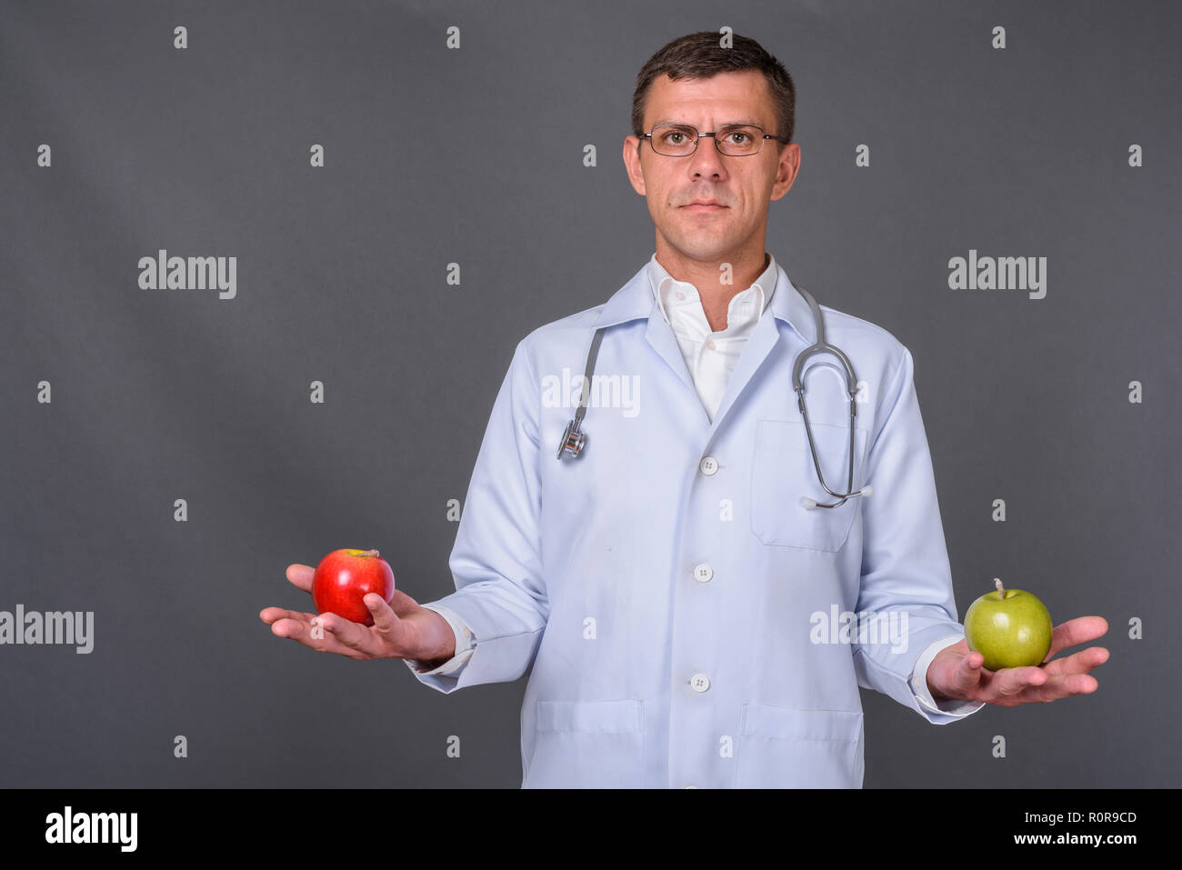 Schöner mann Arzt mit kurzen Haaren gegen grauer Hintergrund Stockfoto