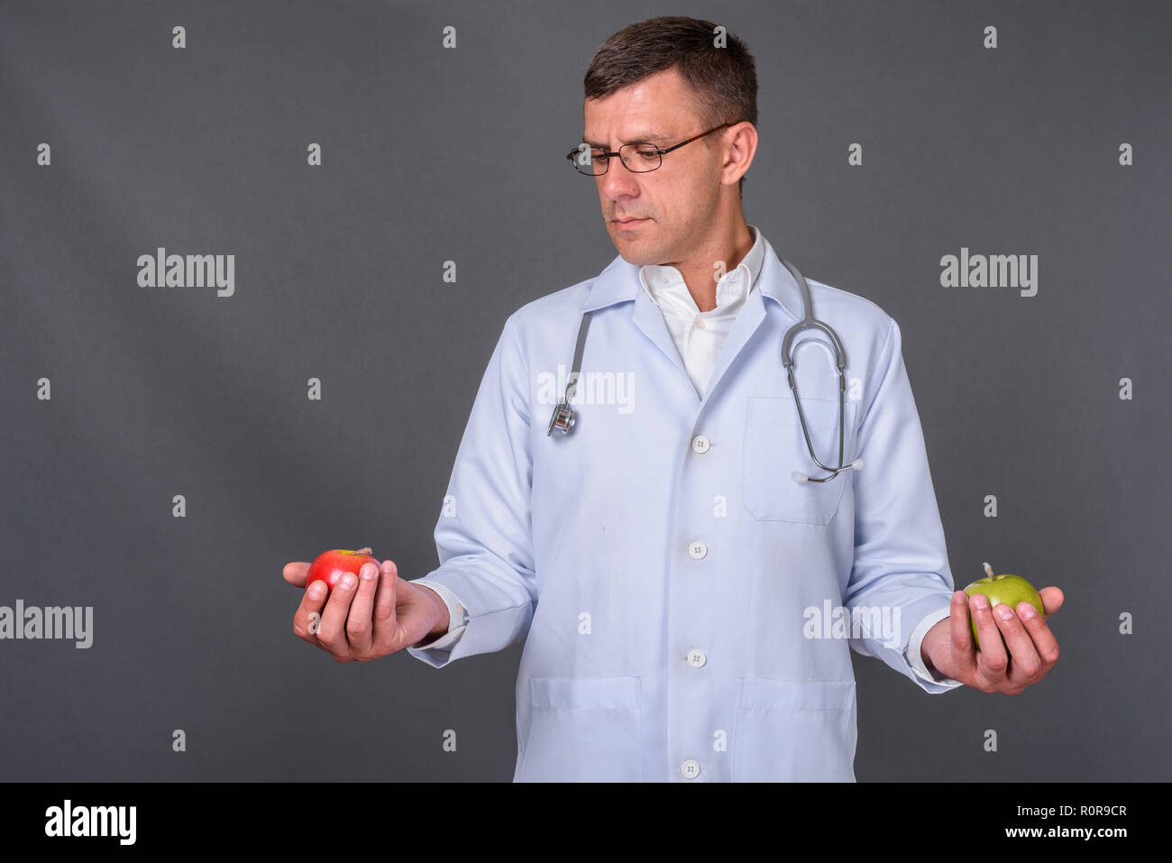 Schöner mann Arzt mit kurzen Haaren gegen grauer Hintergrund Stockfoto