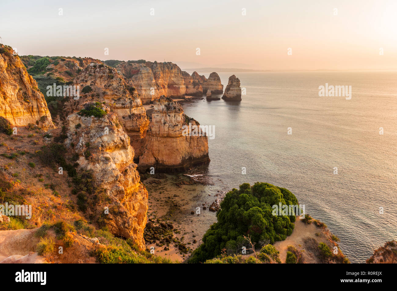 Sonnenaufgang über dem Meer, an der felsigen Küste von Sandstein, Felsformationen im Meer, Algarve, Lagos, Portugal Stockfoto