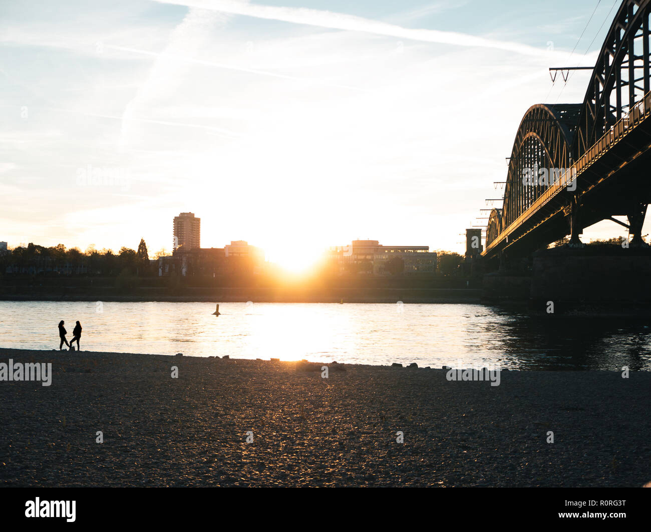 Brücke über den Rhein in Köln bei Sonnenuntergang mit zwei Silhouetten der Frau sprechen Stockfoto