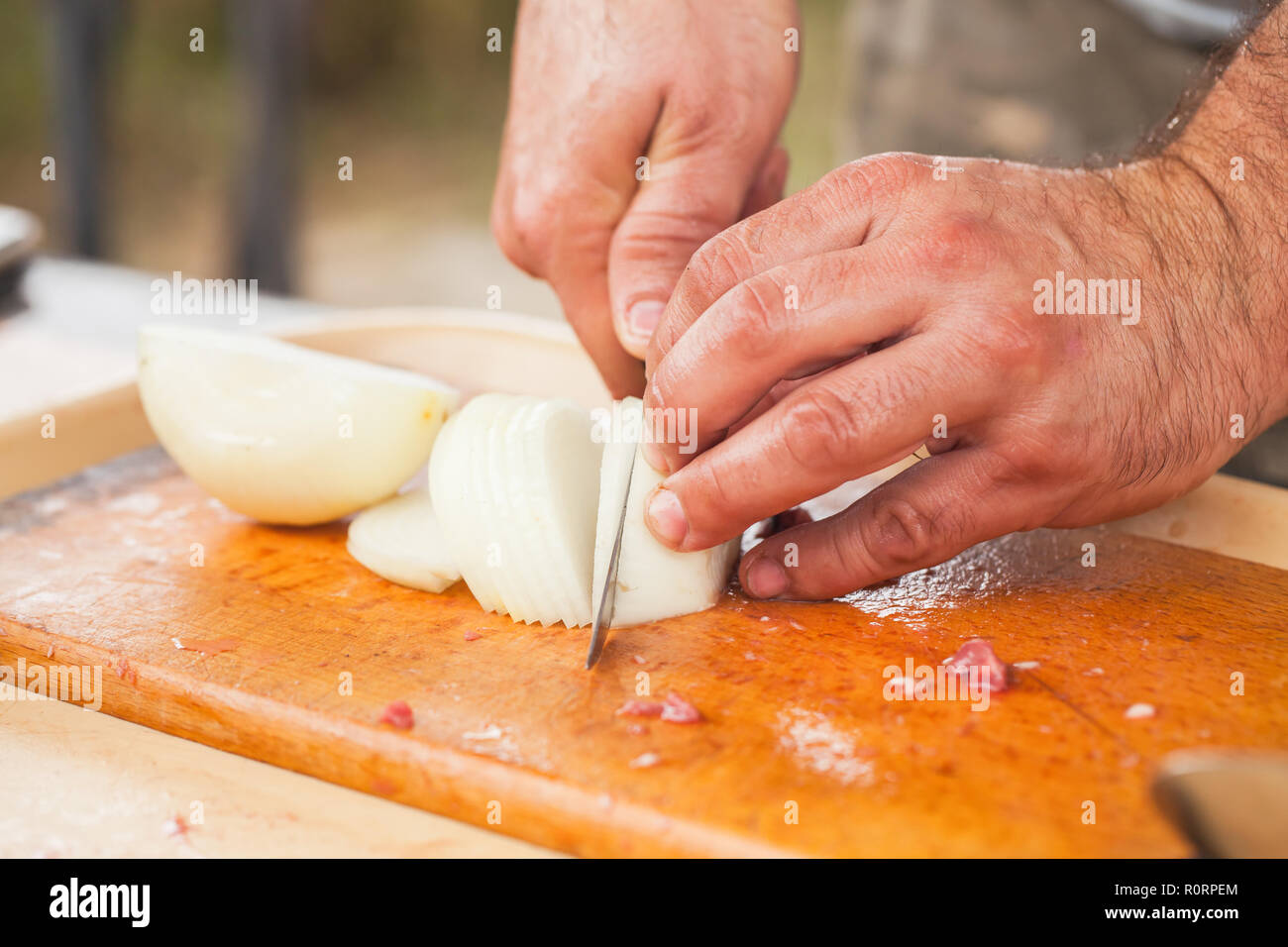 Weiße Zwiebel schneiden. Kochen Hände mit Messer, Nahaufnahme, selektiver Fokus Stockfoto