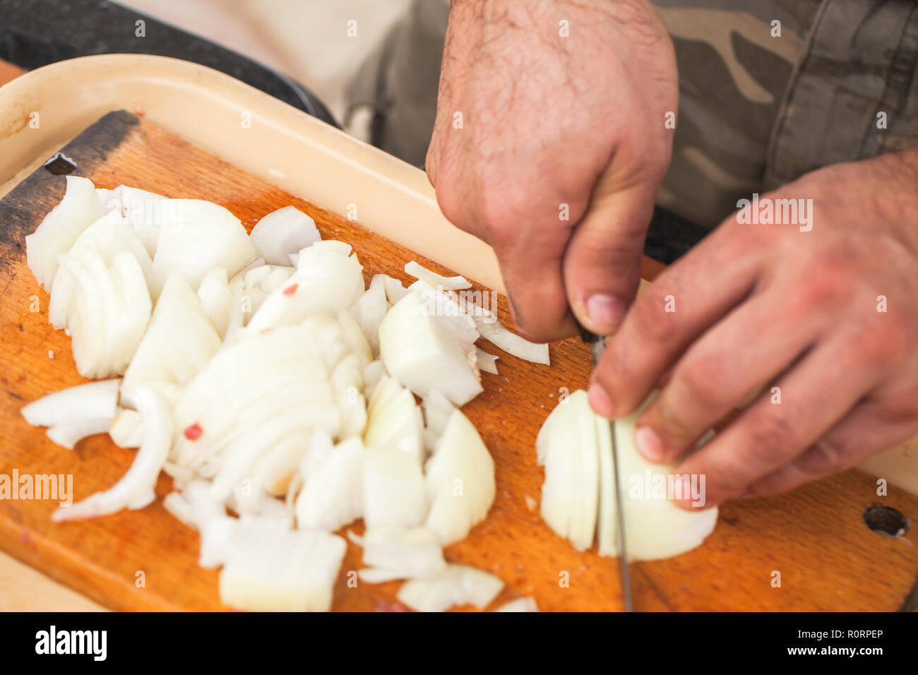 Weiße Zwiebel hacken. Kochen Hände mit Messer, Nahaufnahme, selektiver Fokus Stockfoto