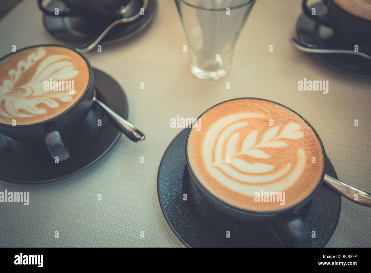 Heiße Kunst latte Kaffee in einer Tasse auf Holztisch und Coffee Shop blur Hintergrund mit bokeh Bild. Latte Art Coffee table top, gerne entspannende Stimmung Stockfoto
