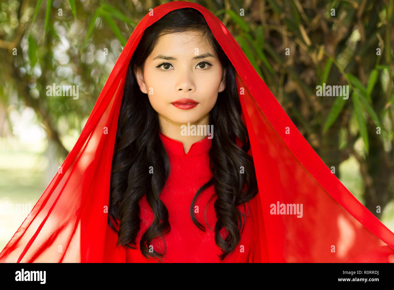 Close up Junge hübsche asiatische Frau im roten Kleid mit Kopftuch mit  Lange wellige Haare in die Kamera schaut Stockfotografie - Alamy