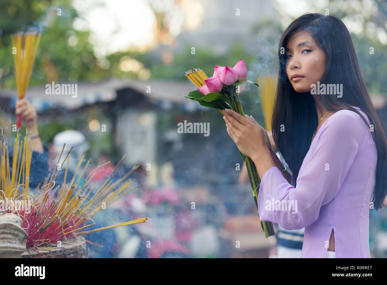 Vietnamesische Frau im Tempel beten, Räucherstäbchen und Lotus Blumen Stockfoto