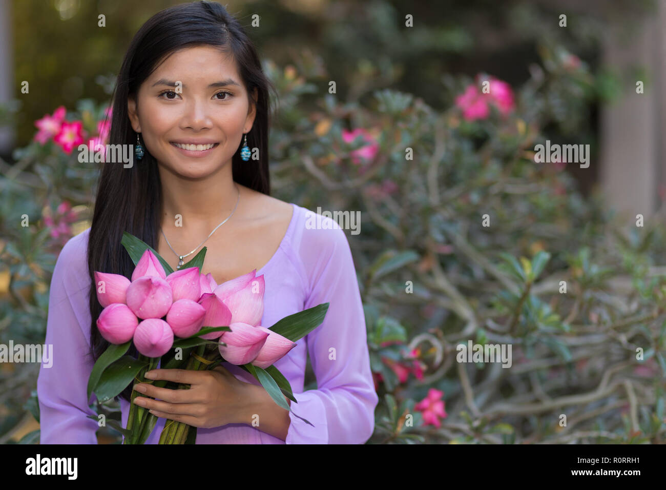 Asiatische Frau mit Lotus Blumen bud vor einer Wüste posing Rose tree Stockfoto
