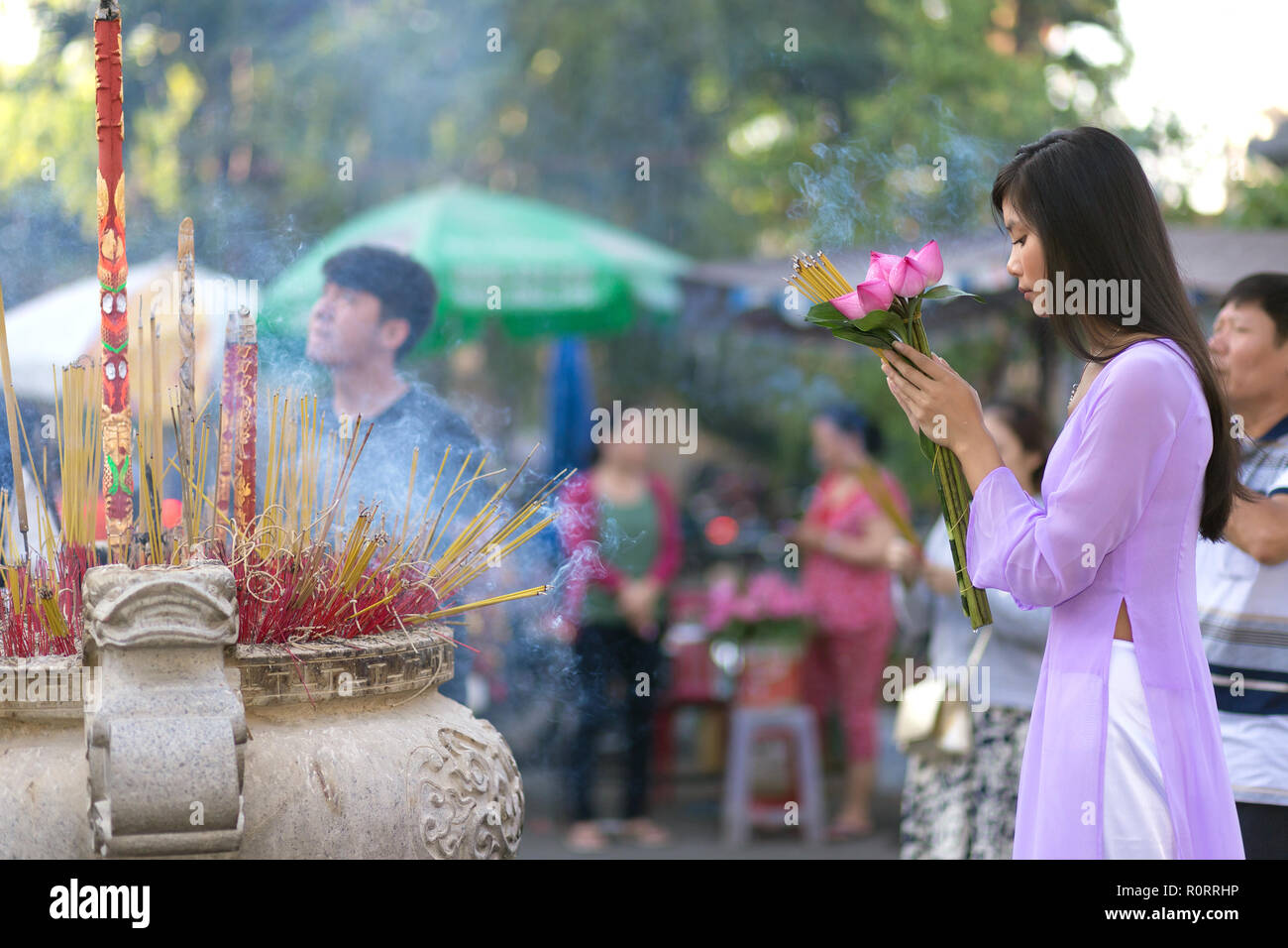 Vietnamesisches Mädchen im Buddhistischen Tempel beten, holding Lotus Blumen, Saigon, Vietnam Stockfoto
