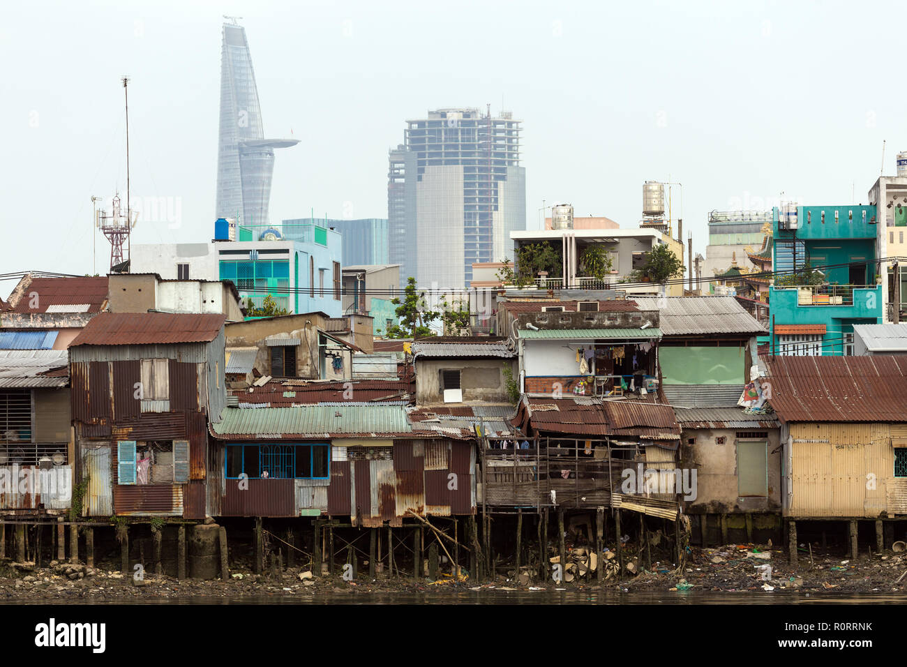 Schlechte shanti Holzhaus auf dem Saigon River Bank, vor modernen Gebäuden, in Ho Chi Minh City, Vietnam Stockfoto