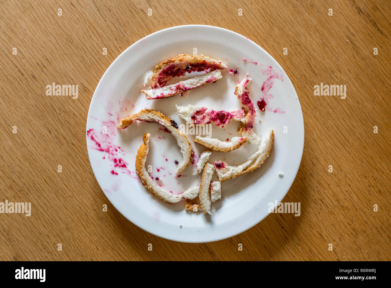 Nicht gefressenes Krusten aus einem Jam Sandwich auf weißem Brot. Stockfoto