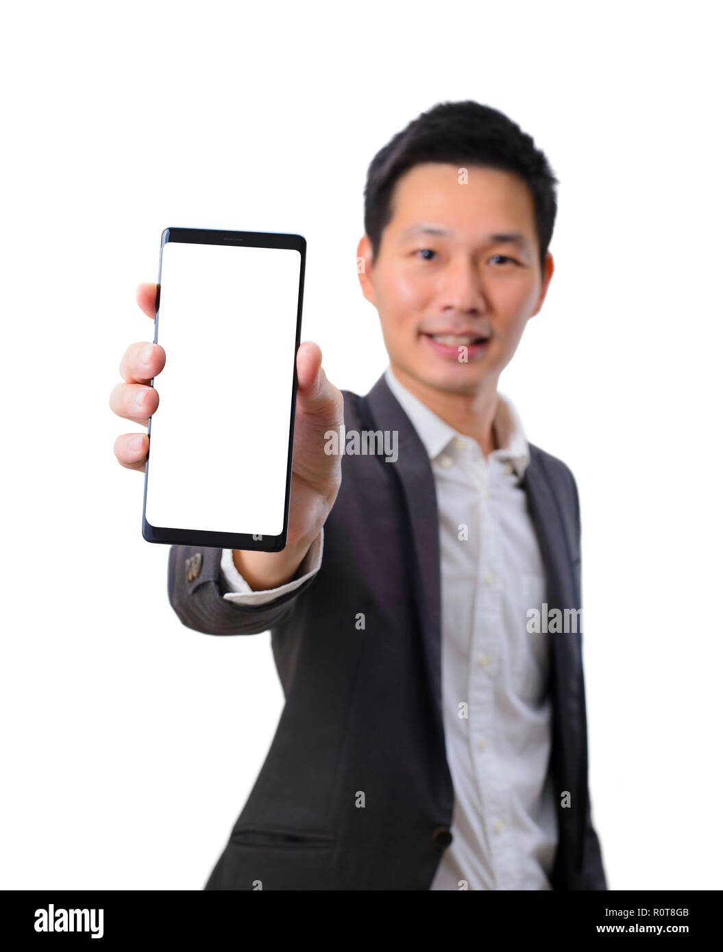 Junge asiatische Geschäftsmann Holding ein Smartphone mit leerer Bildschirm im schwarzen Anzug Stockfoto
