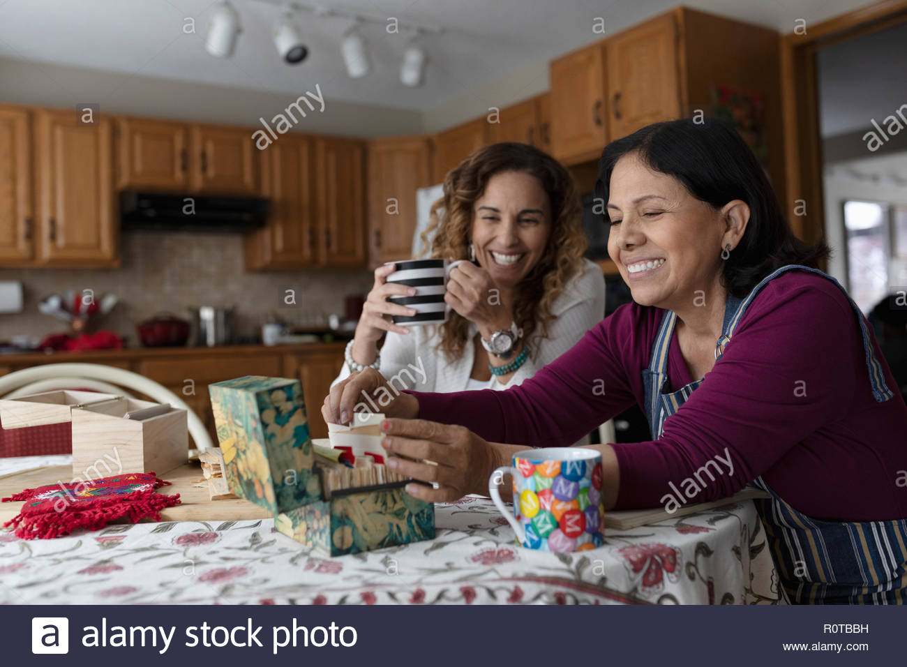 Latinx Tochter und Mutter auf Rezeptbuch in der Küche Stockfoto