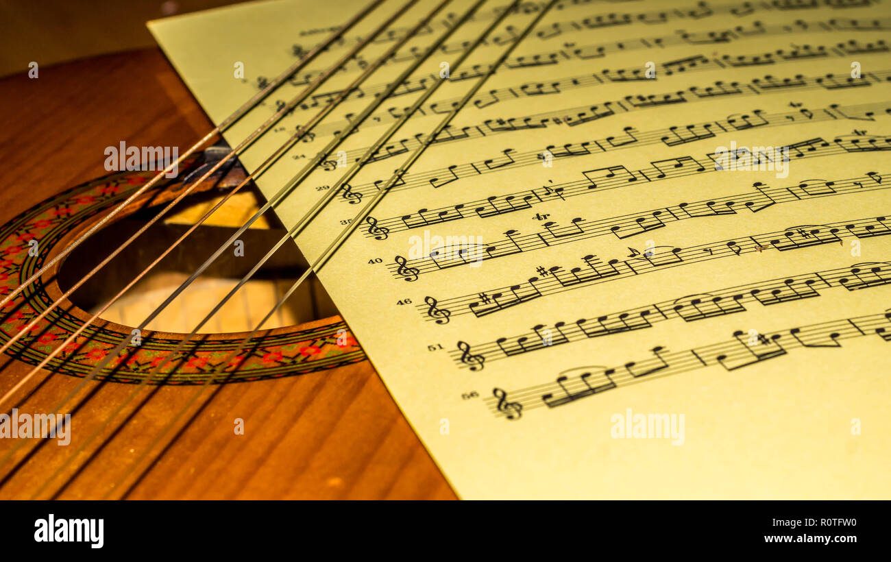 Musik Blatt zwischen Strings und sound Loch einer Akustik Gitarre. Musik und Kunst Hintergrund Stockfoto