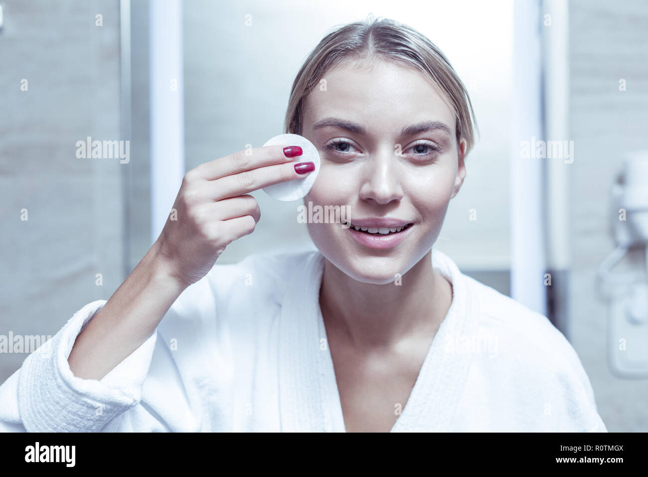 Blue-eyed gut aussehende Frau entfernen Make-up von Gesicht mit Baumwolle Pad Stockfoto