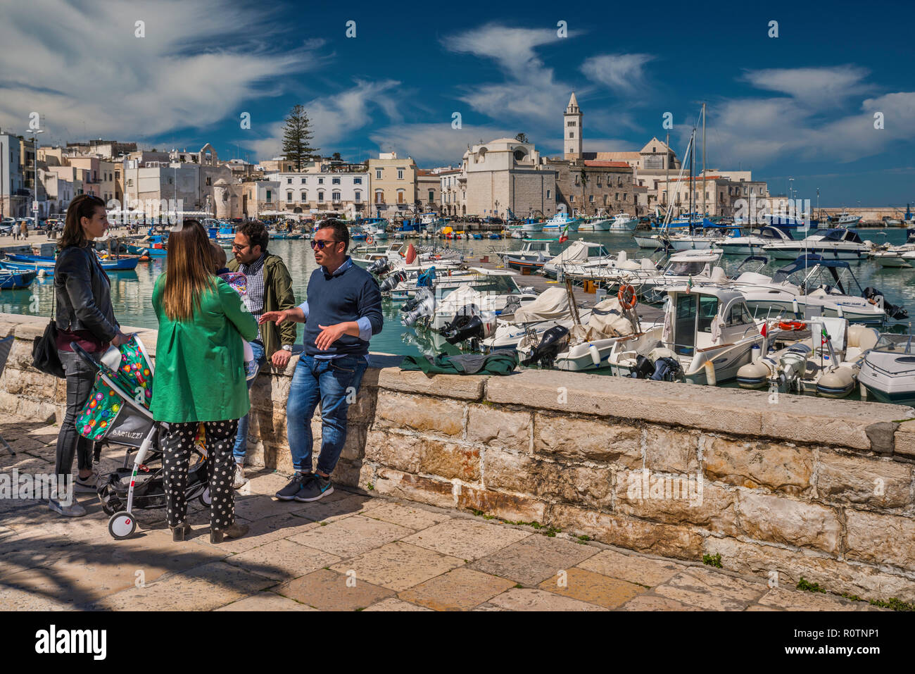 Eine Gruppe von Freunden im Waterfront, das historische Zentrum in Distanz, Trani, Apulien, Italien Stockfoto