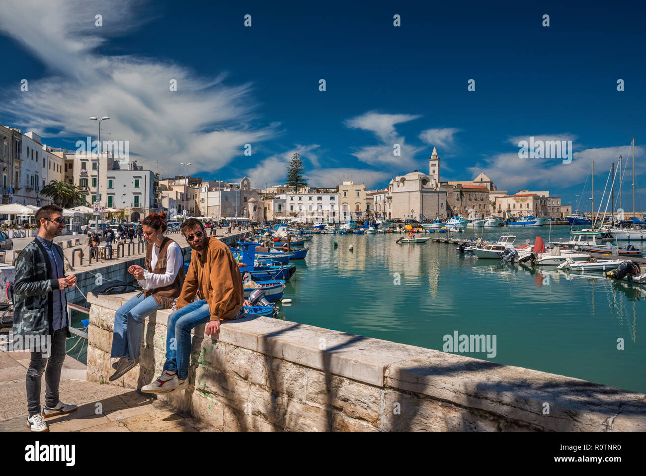 Eine Gruppe von Freunden im Waterfront, das historische Zentrum in Distanz, Trani, Apulien, Italien Stockfoto
