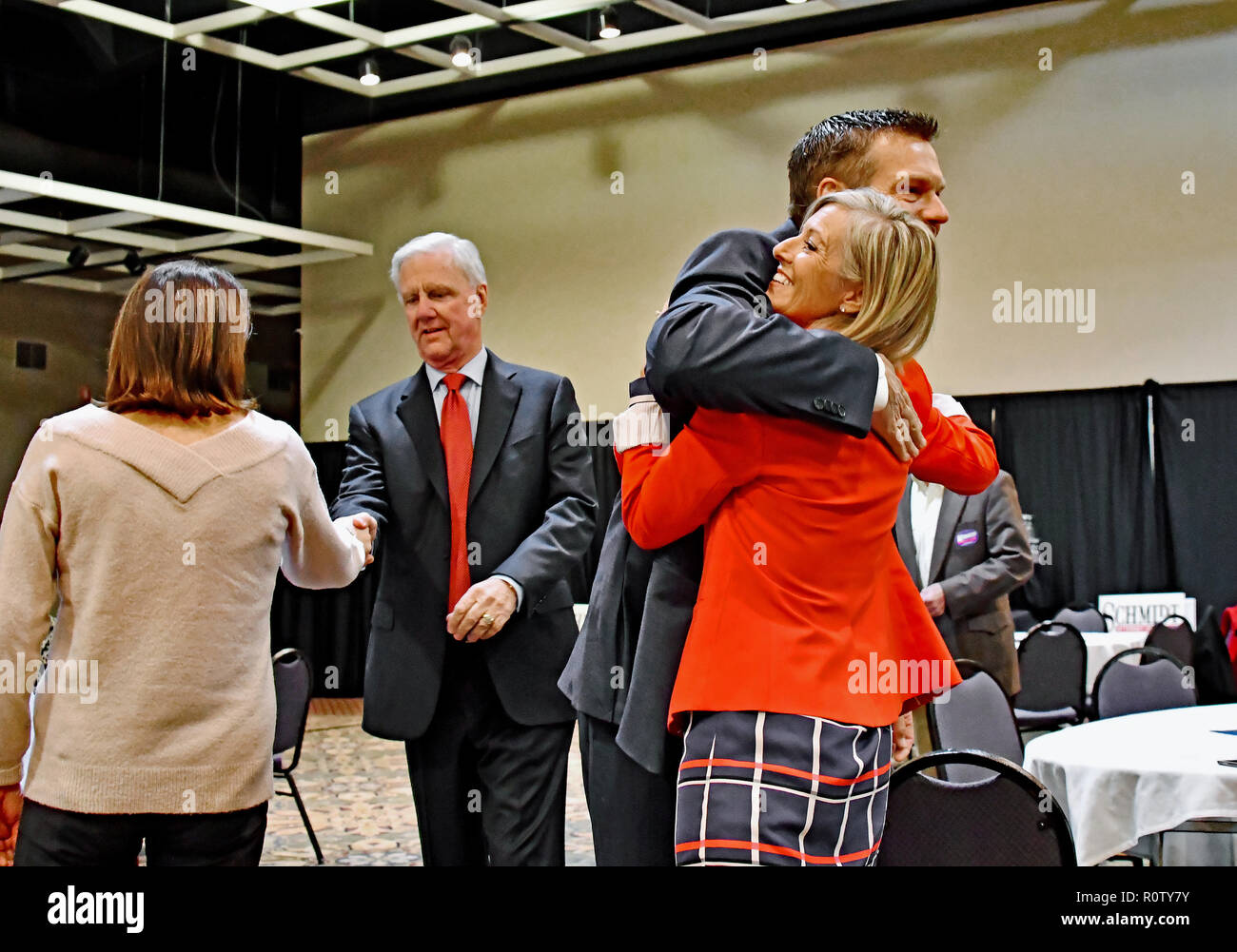 Topeka Kansas, USA, November 6, 2018 Kansas Staatssekretär Kris Kobach erhält eine Umarmung von Kerri Koziol von Overland Park Kansas ist einer der Kampagne Freiwilligen während seine laufenden Gehilfen Wink Hartman Hände schüttelt mit einem anderen Kampagne Unterstützer bei der heutigen Wahl watch Party Stockfoto