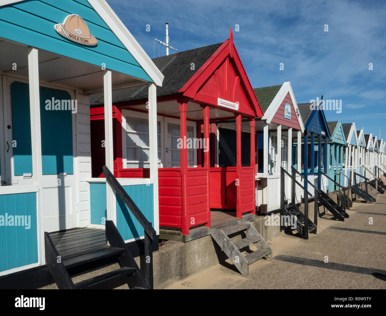Eine Reihe von bunten Badekabinen entlang der Küste von Southwold gegen einen strahlend blauen Himmel Stockfoto