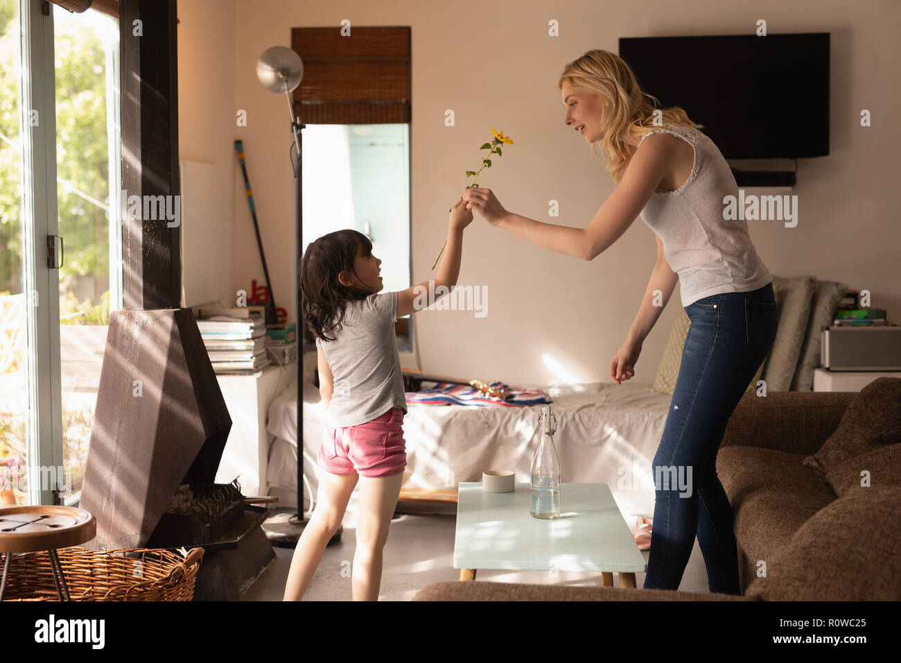 Tochter, eine Blume zu ihrer Mutter im Wohnzimmer Stockfoto