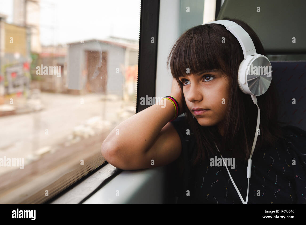 Kleines Madchen Mit Kopfhorern Blick Durch Das Fenster Wahrend Reisen Mit Dem Zug Stockfotografie Alamy