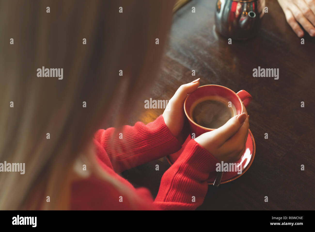 Frau mit Tasse Kaffee auf Tisch Stockfoto