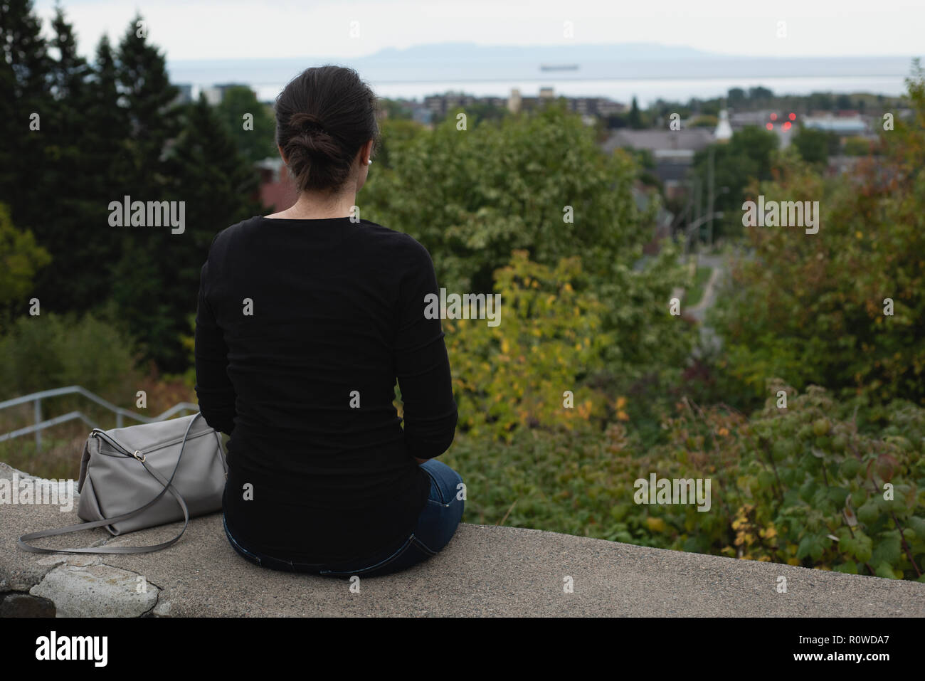 Frau sitzt auf der umgebenden Mauer Stockfoto