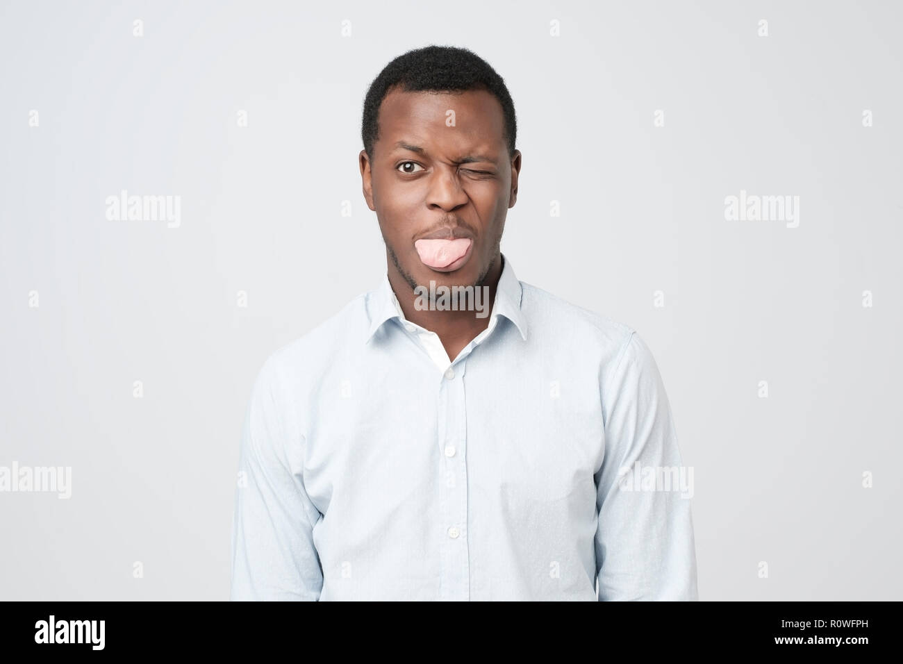 Junge lustig afro-amerikanische Mann macht Grimasse, zeigt Zunge wie Streit mit Freundin. Stockfoto