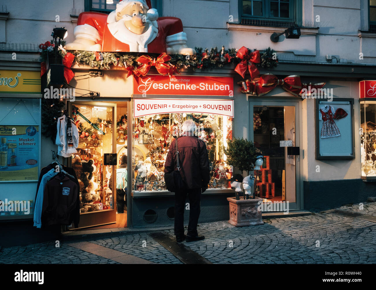 Munich, Bayern, Deutschland - Dezember 6, 2017: Einsame ältere Mann sieht dekorierten Schaufenster mit Geschenke an Heiligabend in der Nacht. Stockfoto