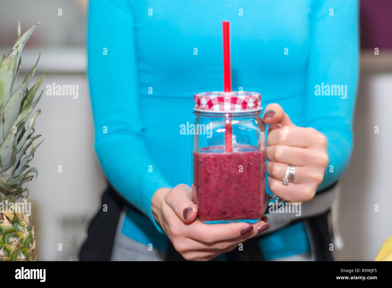 Frau mit Ihrem bevorzugten Rot Smoothie in Händen. Schütteln ist in Mason jar Tassen und mit Rohr. Gesunde und Entgiftung essen und trinken Konzept. Nahaufnahme Stockfoto