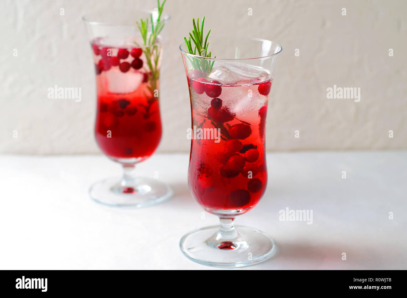 Cranberry Cocktail mit Eis und Rosmarin auf weißem Hintergrund, erfrischendes Getränk Stockfoto