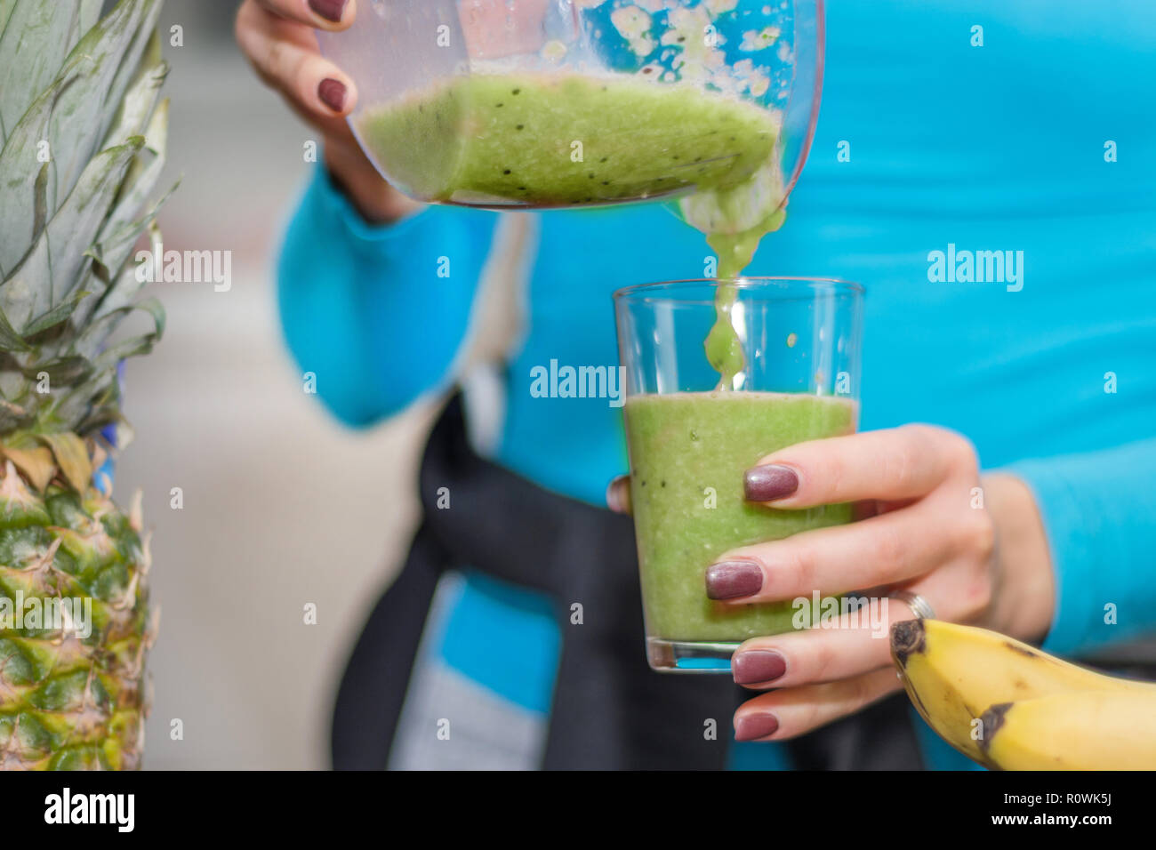 Mädchen gießt ihr Liebling green Smoothie von Blender zu Glas in der Küche zu Hause. Gesunde und Entgiftung essen und trinken Konzept. Close Up, selektiver Fokus Stockfoto