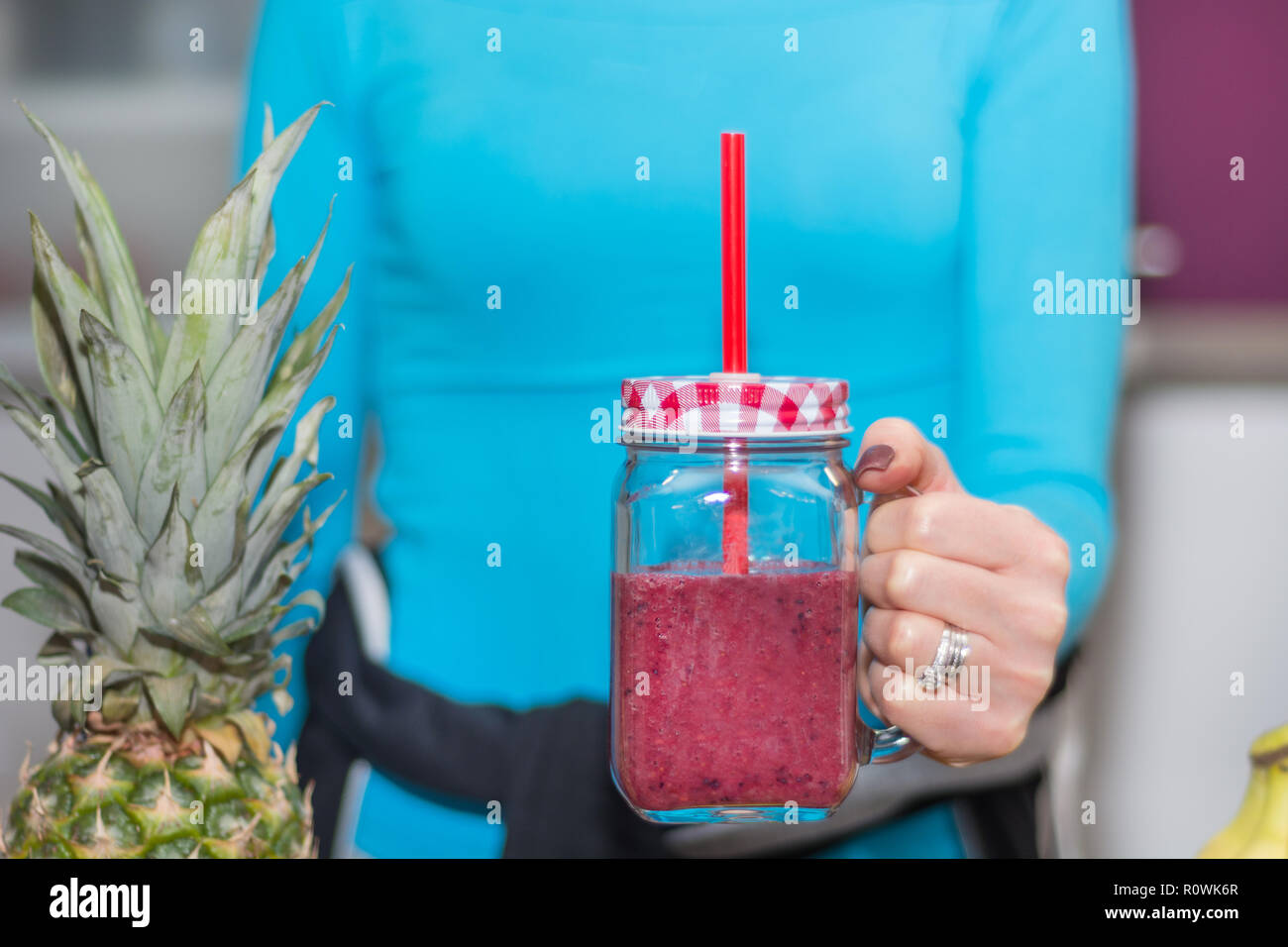 Mädchen mit Mason jar Becher in der Hand mit roten Früchten Smoothie gefüllt. Frau in der Küche zu Hause mit Ihrem Lieblingsgetränk. Detox und gesundes Essen und Trinken Stockfoto