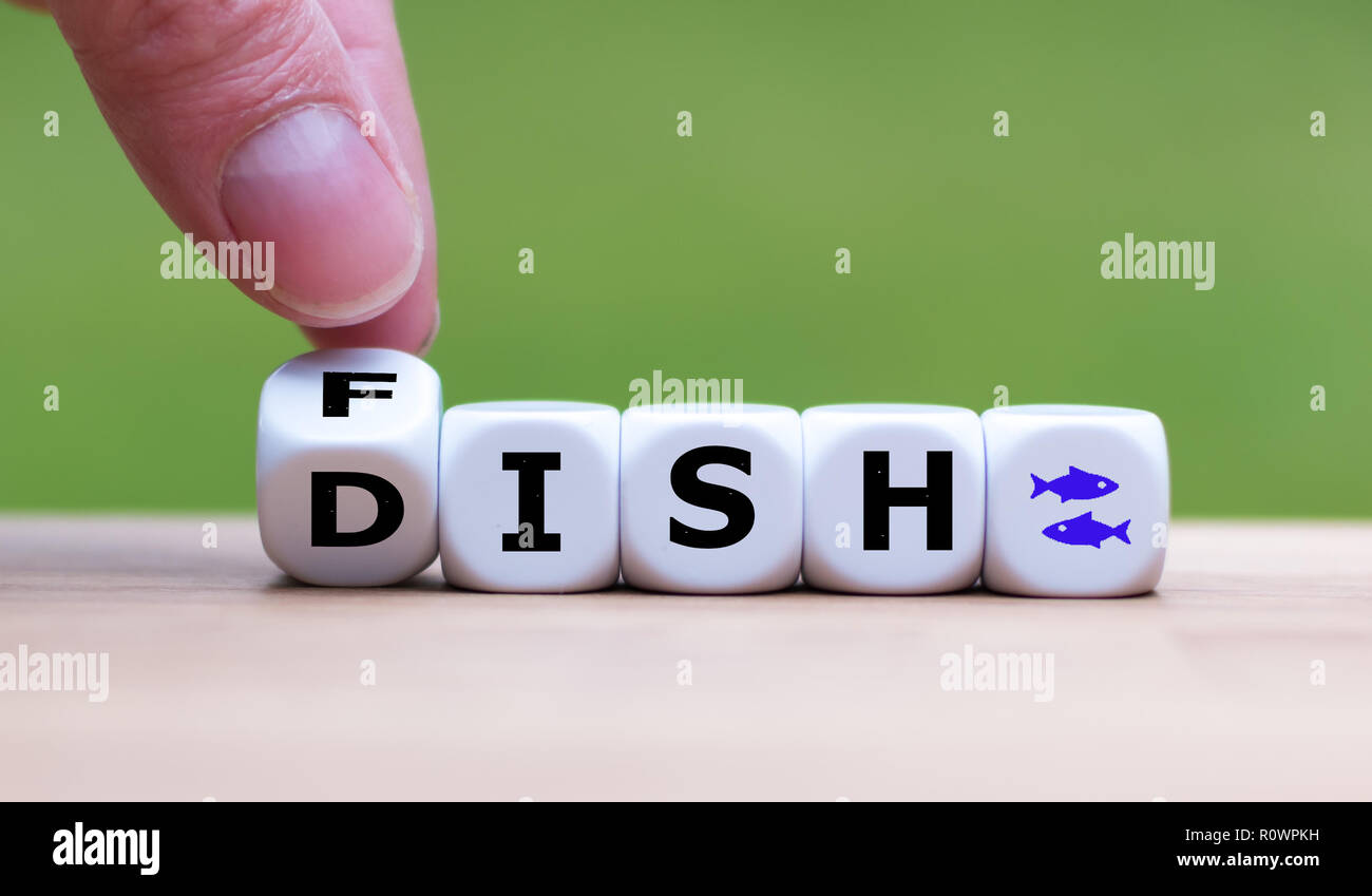 Hand dreht einen Würfel und Änderungen das Wort 'Fisch' zu 'Dish' Stockfoto