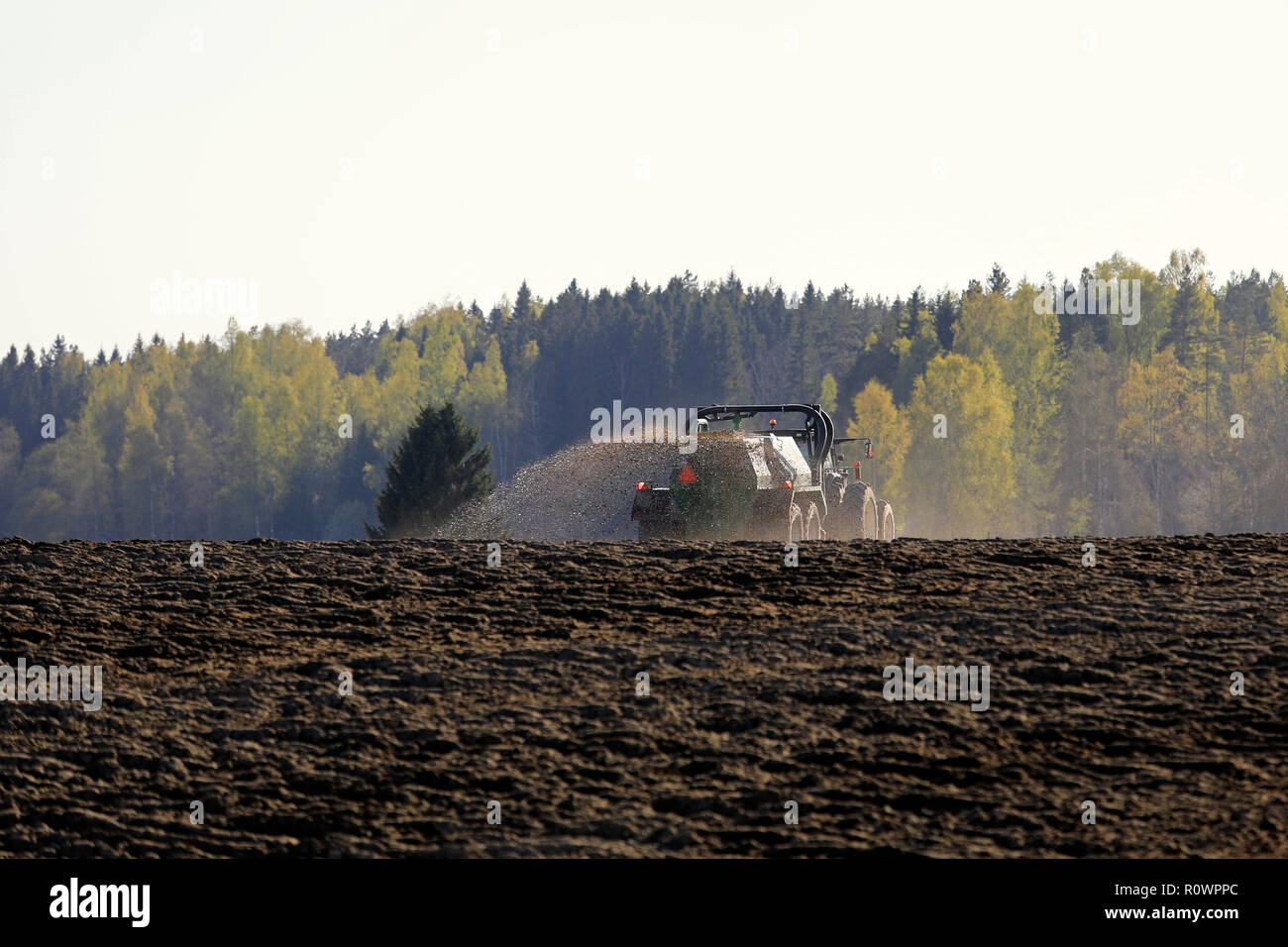 Salo, Finnland - 11. Mai 2018: Bauer Ausbringung von Gülle auf gepflügten Feld mit Traktor und Spreuverteiler auf einem wunderschönen Frühlingsabend im Süden Finnlands. Stockfoto