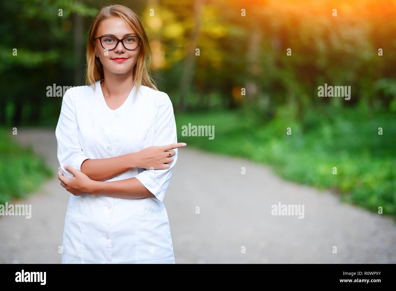 Ein junges Mädchen, die ein Arzt außerhalb steht, zeigt den Zeigefinger der rechten Hand auf der linken Seite. Stockfoto