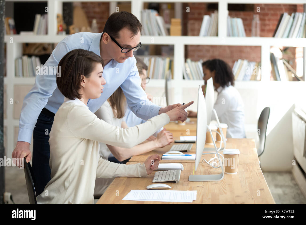 Weibliche Mitarbeiter Punkt auf dem Bildschirm fragen, Ratschläge von Trainer Stockfoto