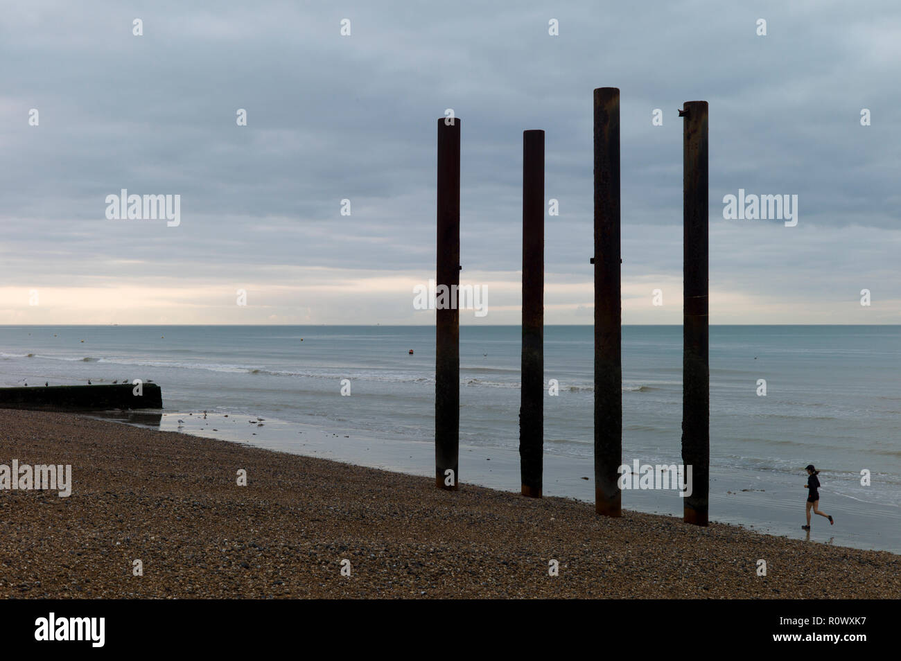 Jogger auf Strand neben Säulen aus ruiniert, Brighton West Pier Stockfoto