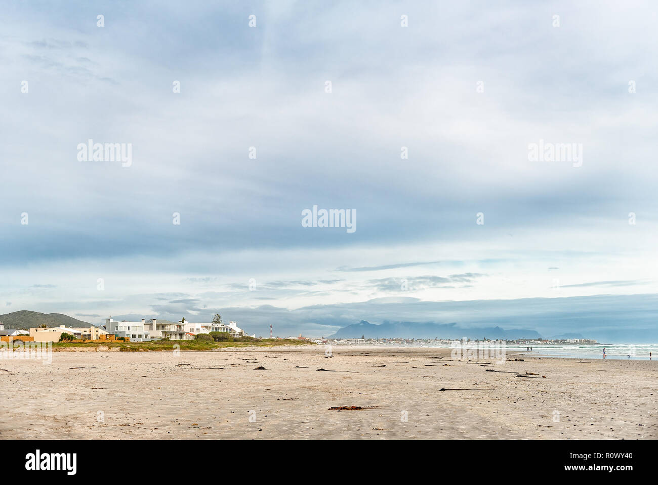 MELKBOSSTRAND, SÜDAFRIKA, 19. AUGUST 2018: eine Strandszene in Melkbosstrand in der Western Cape Provinz. Gebäude, Menschen und den Tafelberg sind vi Stockfoto