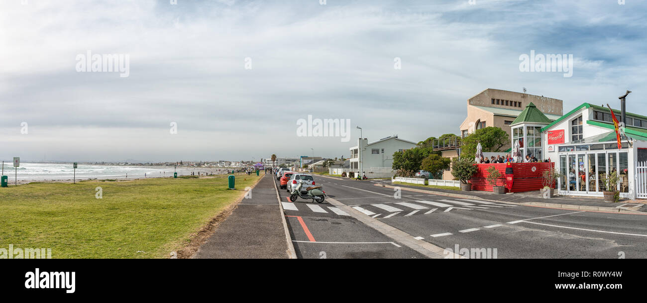 MELKBOSSTRAND, SÜDAFRIKA, 19. AUGUST 2018: eine Straße, Szene, mit Restaurant, Fahrzeuge und Personen, am Strand in Melkbosstrand in der Western Cape Stockfoto